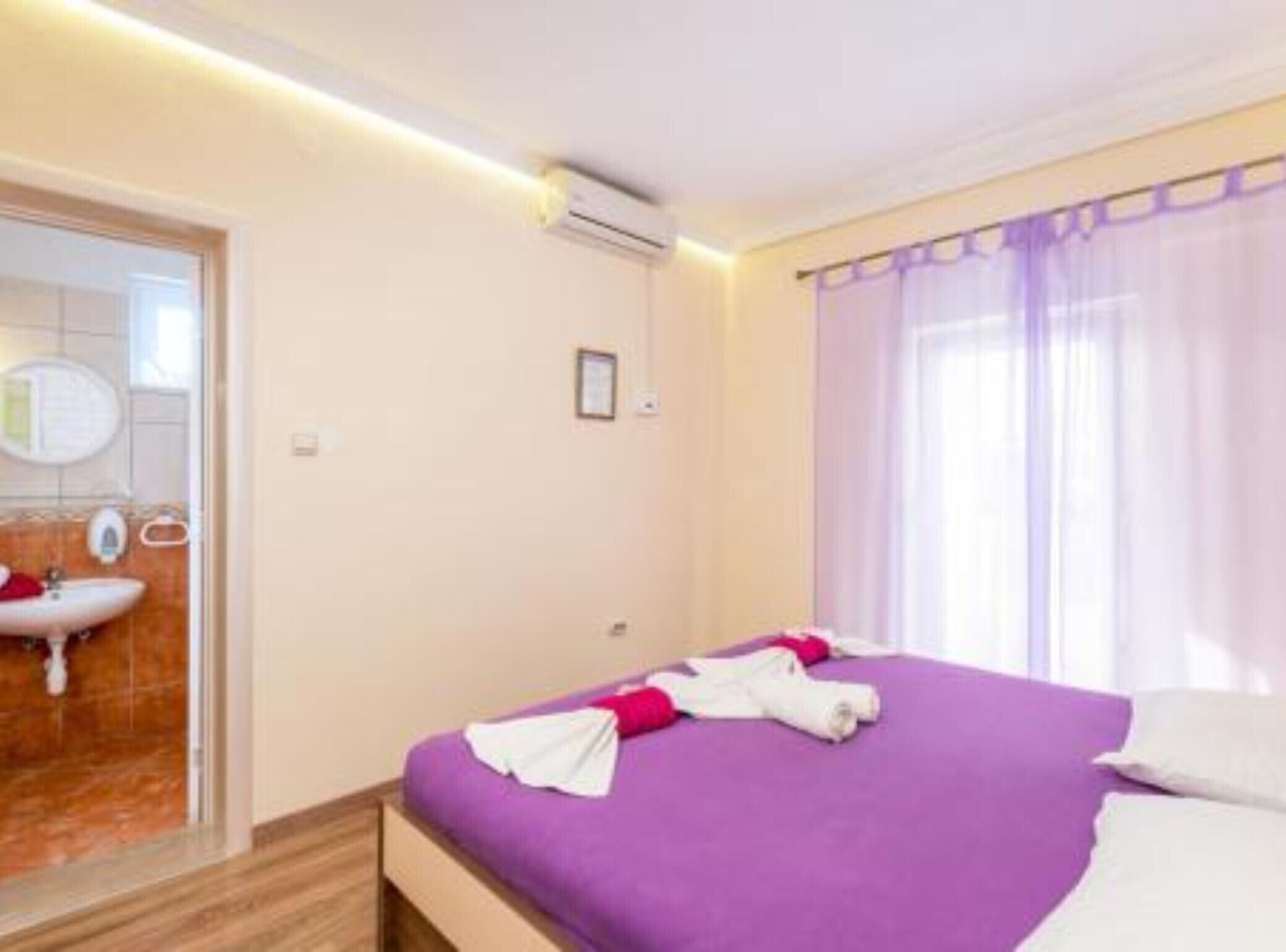 Una habitació d'hotel amb un llit, un bany amb un rentapans i una finestra amb cortines.