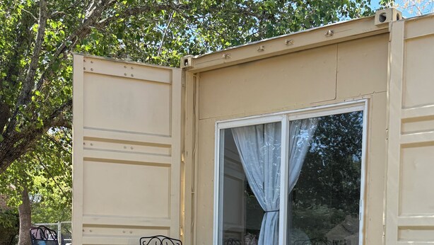 A small, open-sided structure with a deck, seating, and a window with curtains. - Quaint container home on private road 1bd/1bath that can sleep 4 (Wilmington)