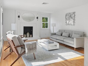 Ein modernes Wohnzimmer mit Kamin, einer Couch, einem Couchtisch und einem Sessel.