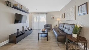 A modern living room with a flat-screen TV, a dark sofa, a coffee table, and a TV stand.