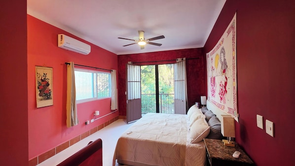 A bedroom with a bed, a ceiling fan, an air conditioning unit, a window with curtains, and a wall with a decorative tapestry. - Casa Efrain + Heated Pool and Rooftop Lounge Near Sayulita & Punta Mita (Higuera Blanca)