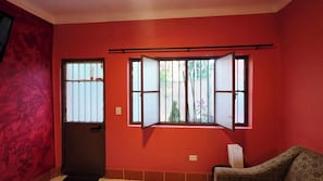 A room with red walls, a closed door, and a window with a view of greenery outside. - Casa Efrain + Heated Pool and Rooftop Lounge Near Sayulita & Punta Mita (Higuera Blanca)