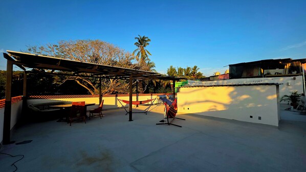An outdoor patio with a pergola, seating, and a hammock.