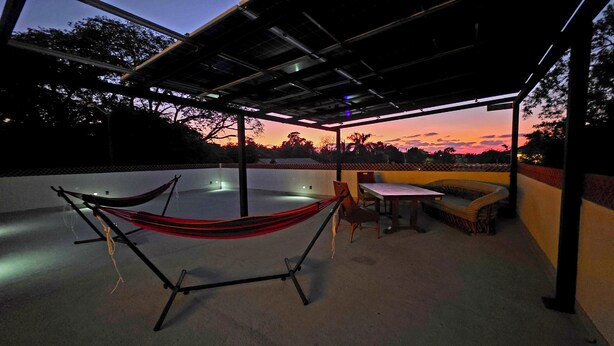 Eine Dachterrasse mit Hängematte, Tisch und einer Couch.