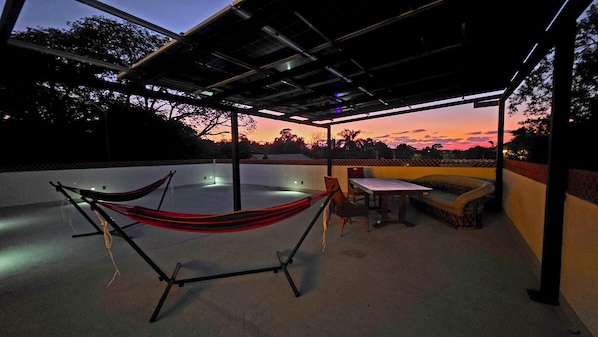 Una terraza en la azotea con una hamaca, una mesa y un sofá.