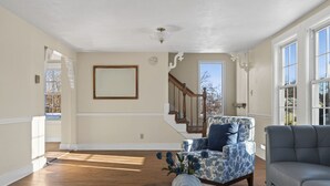 A spacious living room with hardwood floors, a staircase, and a large window. - Gorgeous Downtown Townhome - Walk to Beach (Old Orchard Beach)