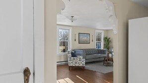 A living room with a grey sofa, patterned armchair, and a painting on the wall. - Gorgeous Downtown Townhome - Walk to Beach (Old Orchard Beach)