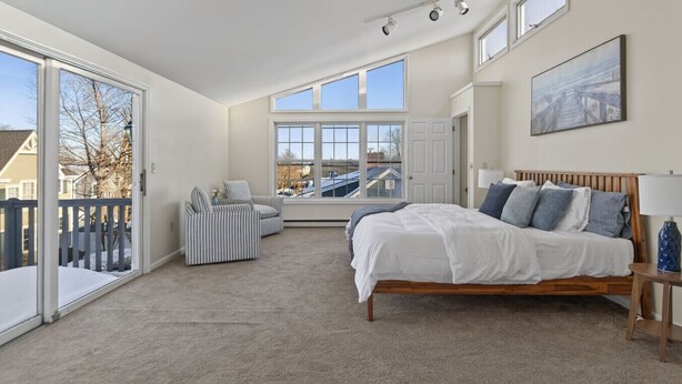 A bedroom with a large bed, a chair, a window, and a door. - Gorgeous Downtown Townhome - Walk to Beach (Old Orchard Beach)