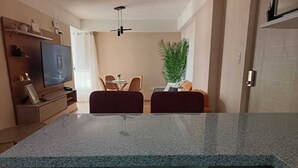 Eine moderne Küche mit Granit-Arbeitsplatten, einem Essbereich mit zwei Stühlen, einem Fernseher und einem Blumentopf.