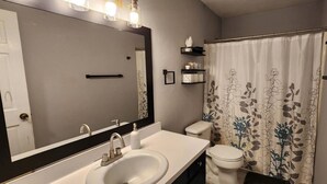 A bathroom with a white sink, a toilet, and a shower curtain with a floral pattern. - 2BR Near Sherman College, Wi-Fi + Washer/Dryer (Boiling Springs)