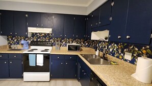 A kitchen with dark blue cabinets, a white stove, a microwave, and a sink. - 2BR Near Sherman College, Wi-Fi + Washer/Dryer (Boiling Springs)