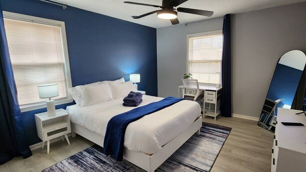 A modern bedroom with a bed, bedside tables, a desk, and a large mirror. - 2BR Near Sherman College, Wi-Fi + Washer/Dryer (Boiling Springs)
