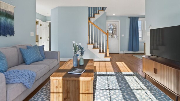 Ein Wohnzimmer mit Sofa, Couchtisch, Fernseher und Treppe.