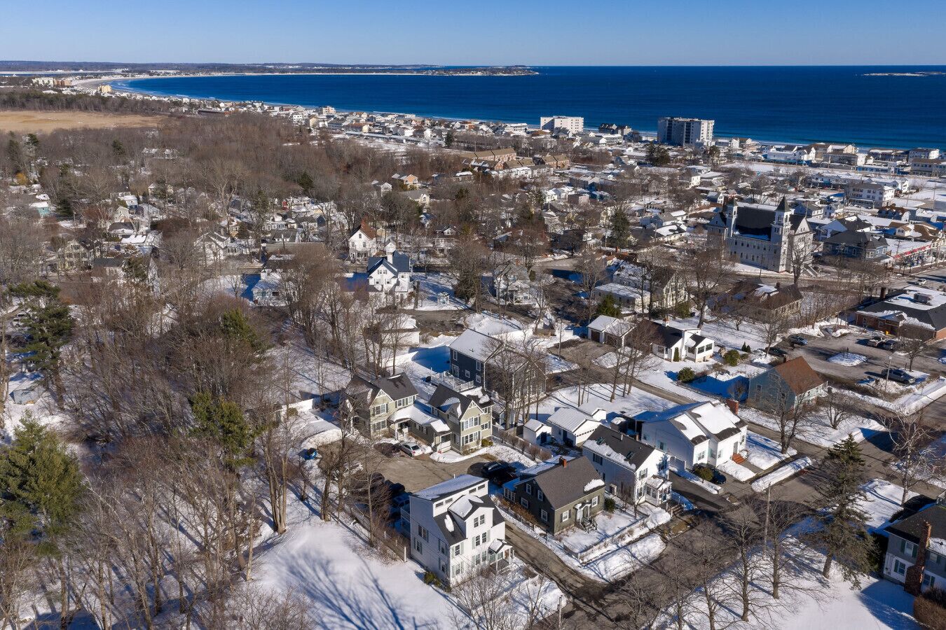 A residential area with houses, a clear sky, and a distant view of the ocean.