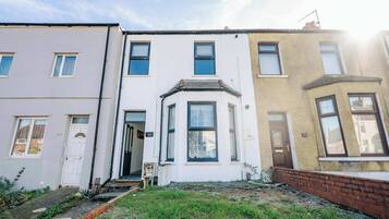 A row of terraced houses with front doors, numbered 104 and 102, and a small garden area in front.
