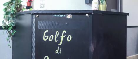 Un mostrador de recepción con el texto "Reception" y "Golf di Orosei ROMA".