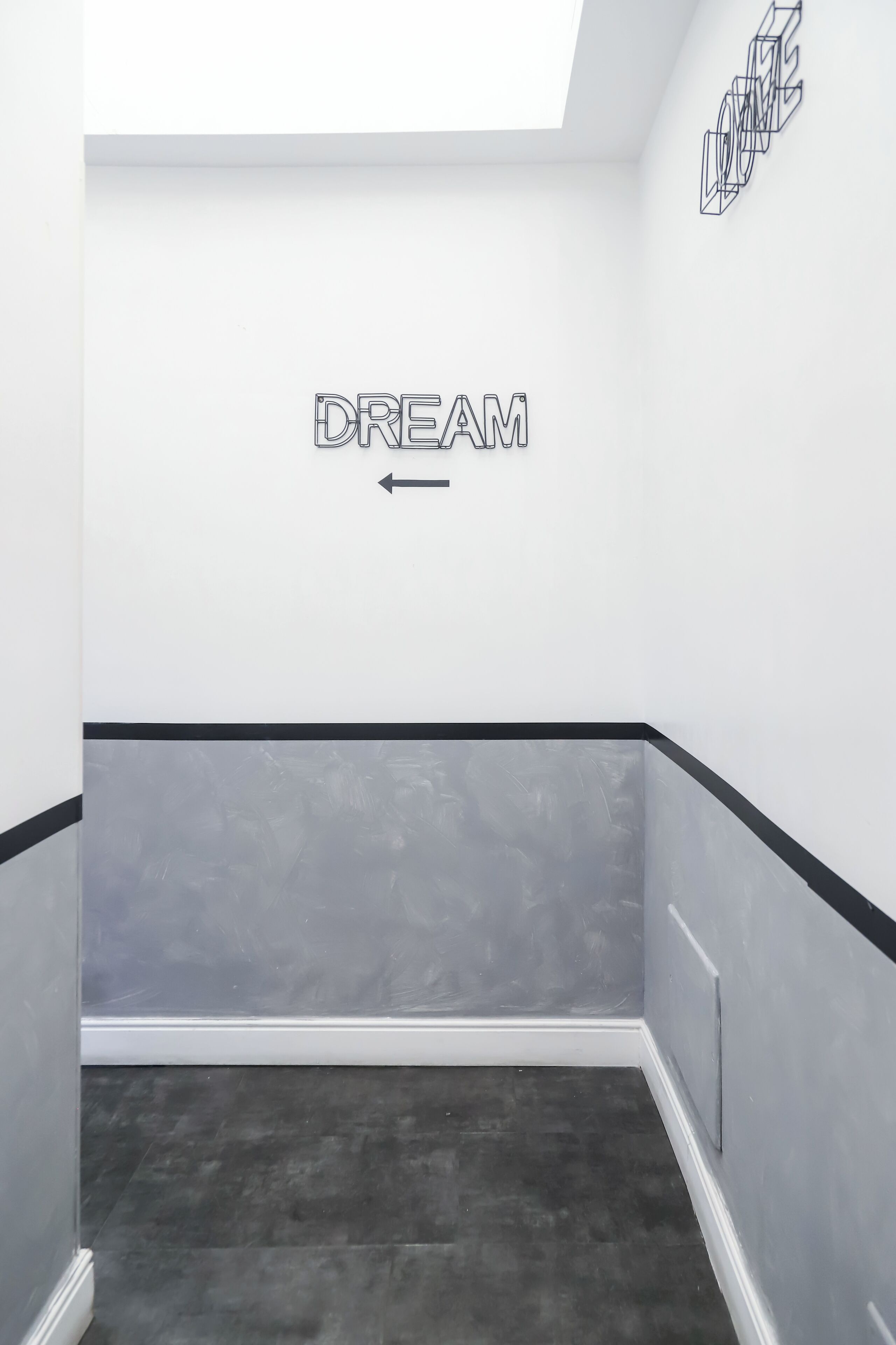Un pasillo con un cartel que dice 'DREAM' en la pared y una obra de arte geométrica encima.