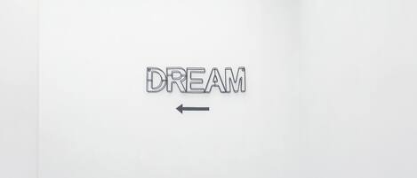 Un pasillo con un cartel que dice 'DREAM' en la pared y una obra de arte geométrica encima.