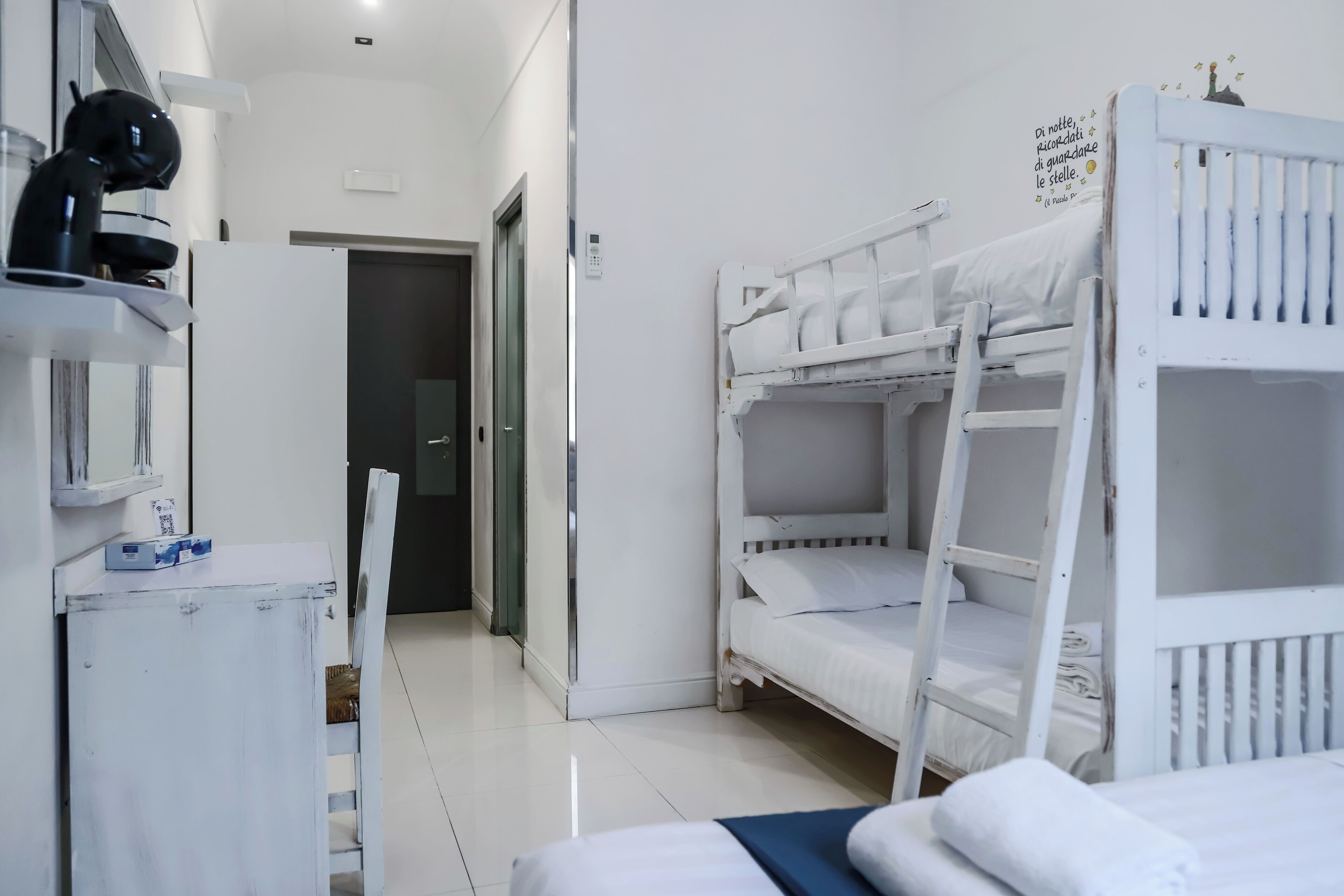 A room with bunk beds, a desk with a chair, and a microwave.