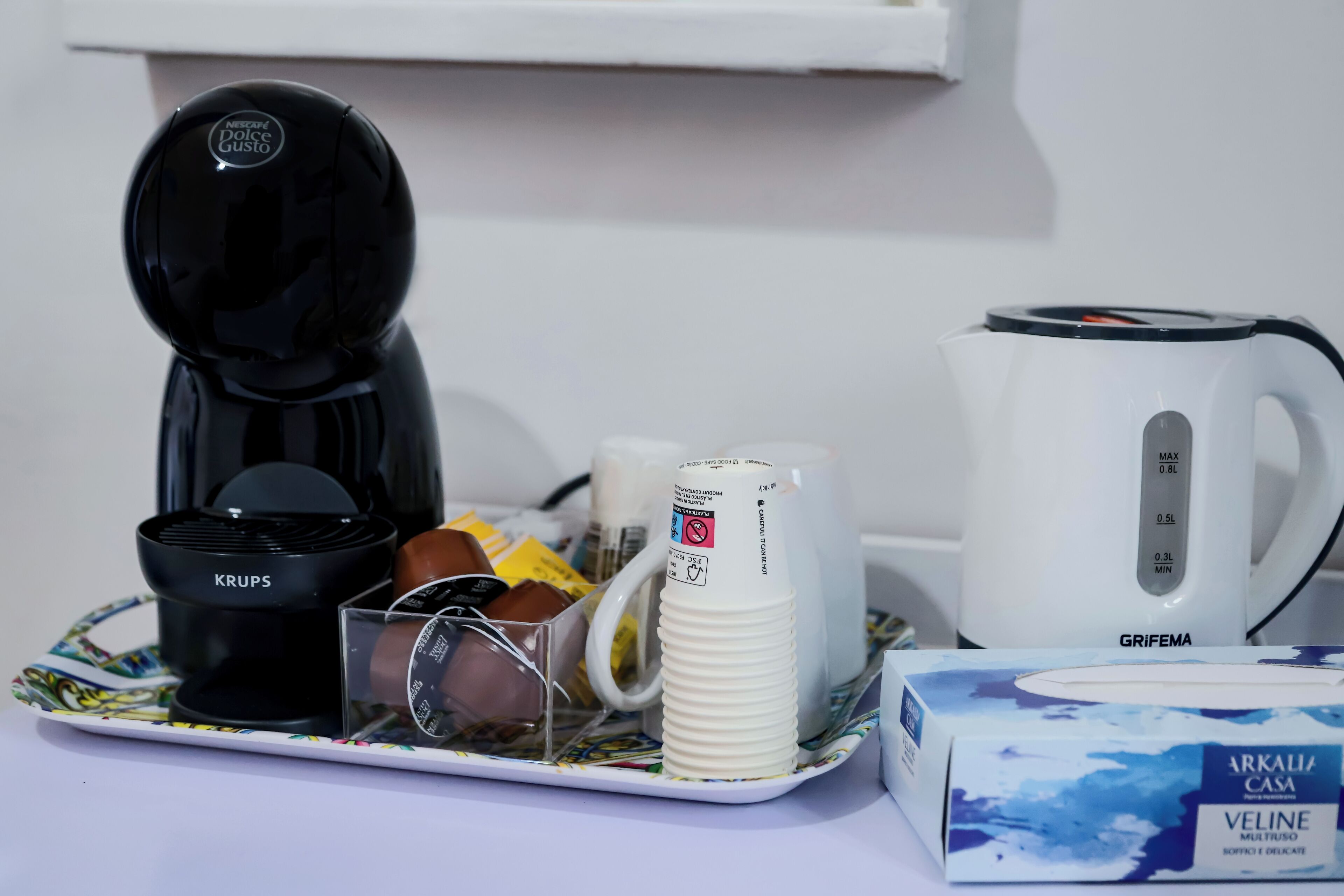 Eine Kaffeemaschine, ein Wasserkocher, eine Tasse, eine Schachtel und ein Teller mit Tassenhalter.
