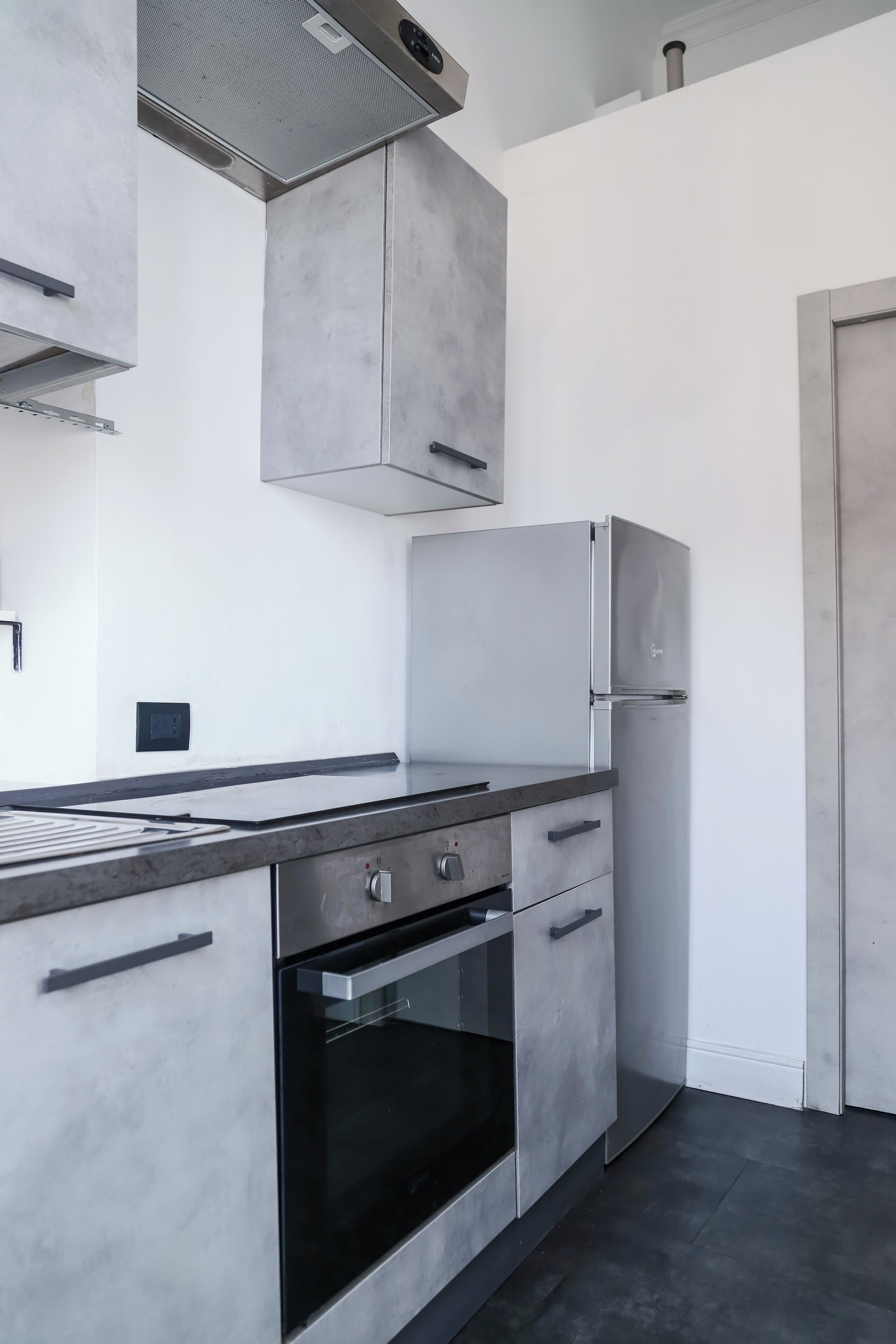 A modern kitchen with a stainless steel refrigerator, built-in oven, and a sleek countertop.
