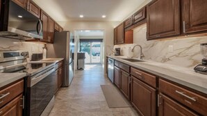 A modern kitchen with dark wood cabinets, stainless steel appliances, and a marble countertop. - 2 King Beds, Kitchen, Living & Dining Room, Yard, Heated Pool, WiFi, Apt#2112 (Wilton Manors)