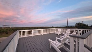 A wooden deck with white railings and several Adirondack chairs. - Cozy Cottage w/ Gorgeous Views - Near the beach! (Galveston)
