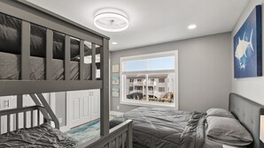 Ein Schlafzimmer mit Etagenbetten, einem Fenster mit Blick auf ein Gebäude und einer Deckenleuchte.