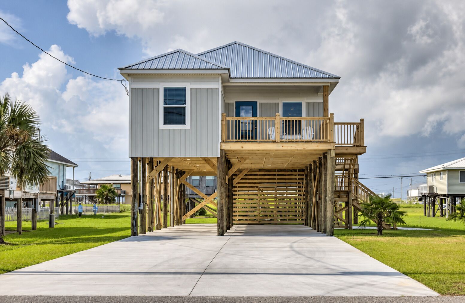 A two-story house with a balcony, elevated wooden deck, and a concrete driveway.