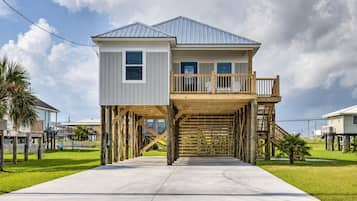 A two-story house with a balcony, elevated wooden deck, and a concrete driveway.