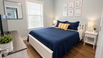 A bedroom with a bed, bedside tables, a mirror, and wall art.