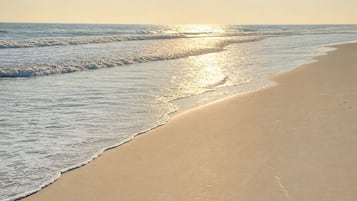A beach with a clear sky and the sun shining.