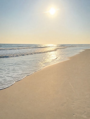A beach with a clear sky and the sun shining.