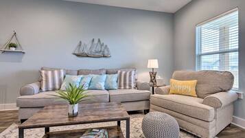 A living room with a sofa, a coffee table, and a window with blinds.