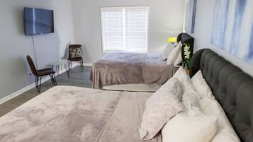 A bedroom with two beds, a TV, a chair, and a window.