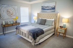 Une chambre à coucher avec un grand lit, deux tables de chevet, une commode, un bureau et une chaise.