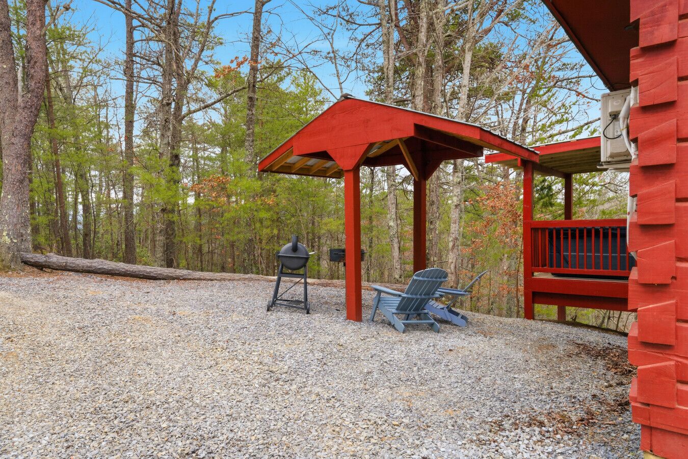 A covered outdoor seating area with a grill, a chair, and a wooden deck.