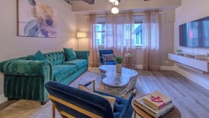A living room with a green sofa, a blue chair, a coffee table, and a TV.