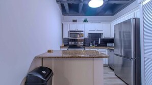 A kitchen with white cabinets, a stainless steel refrigerator, a microwave, and a stove.