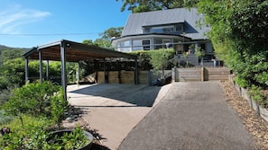 A covered outdoor area with a concrete floor, surrounded by greenery and a house in the background. - Bay views with a secluded bush backdrop (HARDYS BAY)