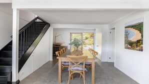 A dining area with a wooden table and chairs, a staircase, and a painting on the wall. - Bay views with a secluded bush backdrop (HARDYS BAY)