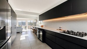 A modern kitchen with black cabinets, a white countertop, and a built-in stove. - Bay views with a secluded bush backdrop (HARDYS BAY)