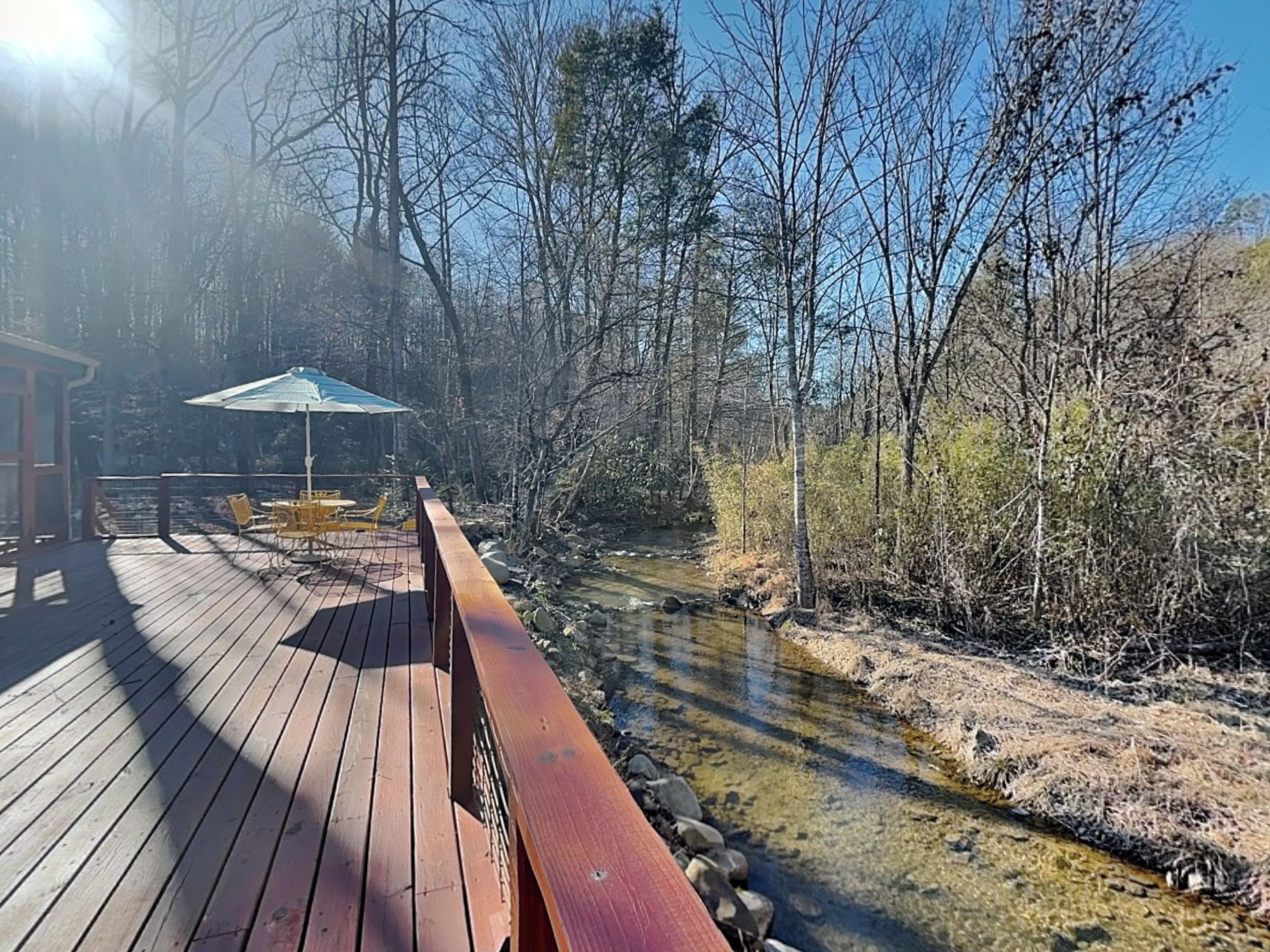 Une terrasse en bois avec des sièges extérieurs et une vue sur une rivière.