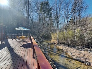Une terrasse en bois avec des sièges extérieurs et une vue sur une rivière.