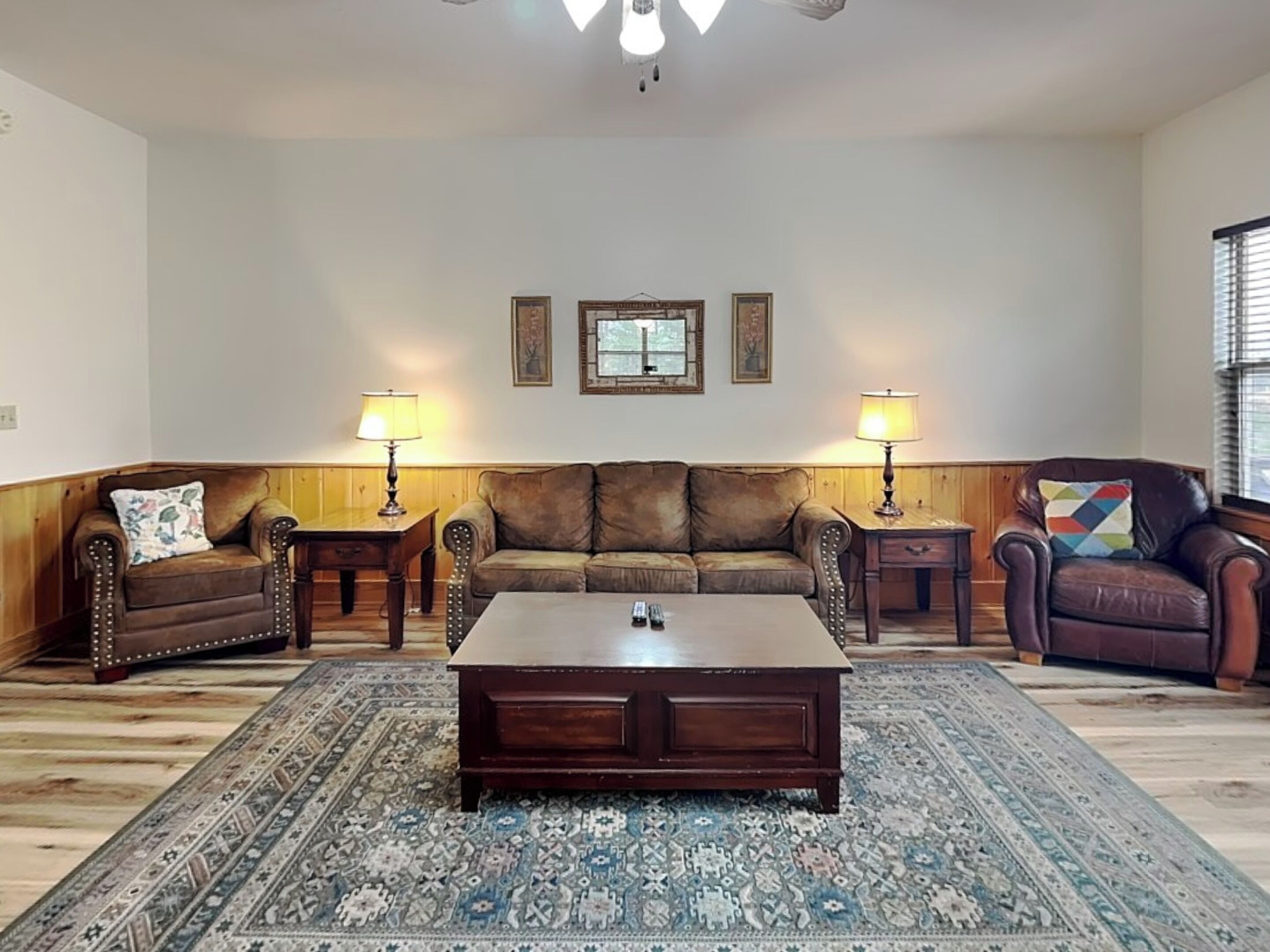 A living room with a brown leather sofa, two armchairs, a coffee table, and two lamps.