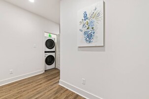 A laundry room with a washing machine and dryer, a white wall, and a framed artwork.