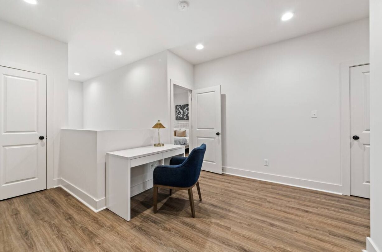 A room with a white desk, a blue chair, and a lamp.