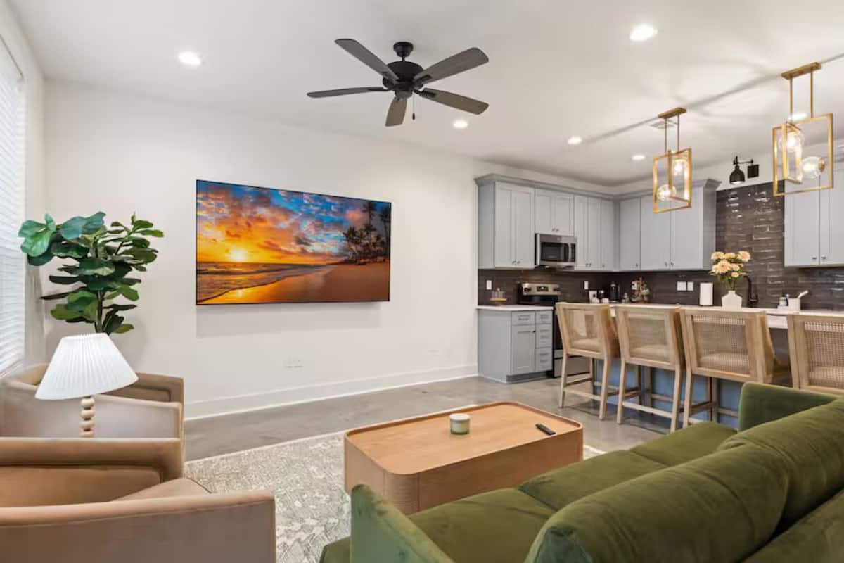 A modern living room with a sofa, a coffee table, and a painting of a sunset.
