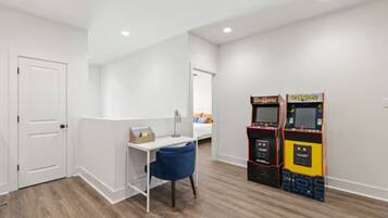 Una habitación de hotel con una puerta blanca, un escritorio con una silla y dos máquinas recreativas.