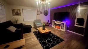 Ett modernt vardagsrum med en soffa, ett soffbord och en tv.
